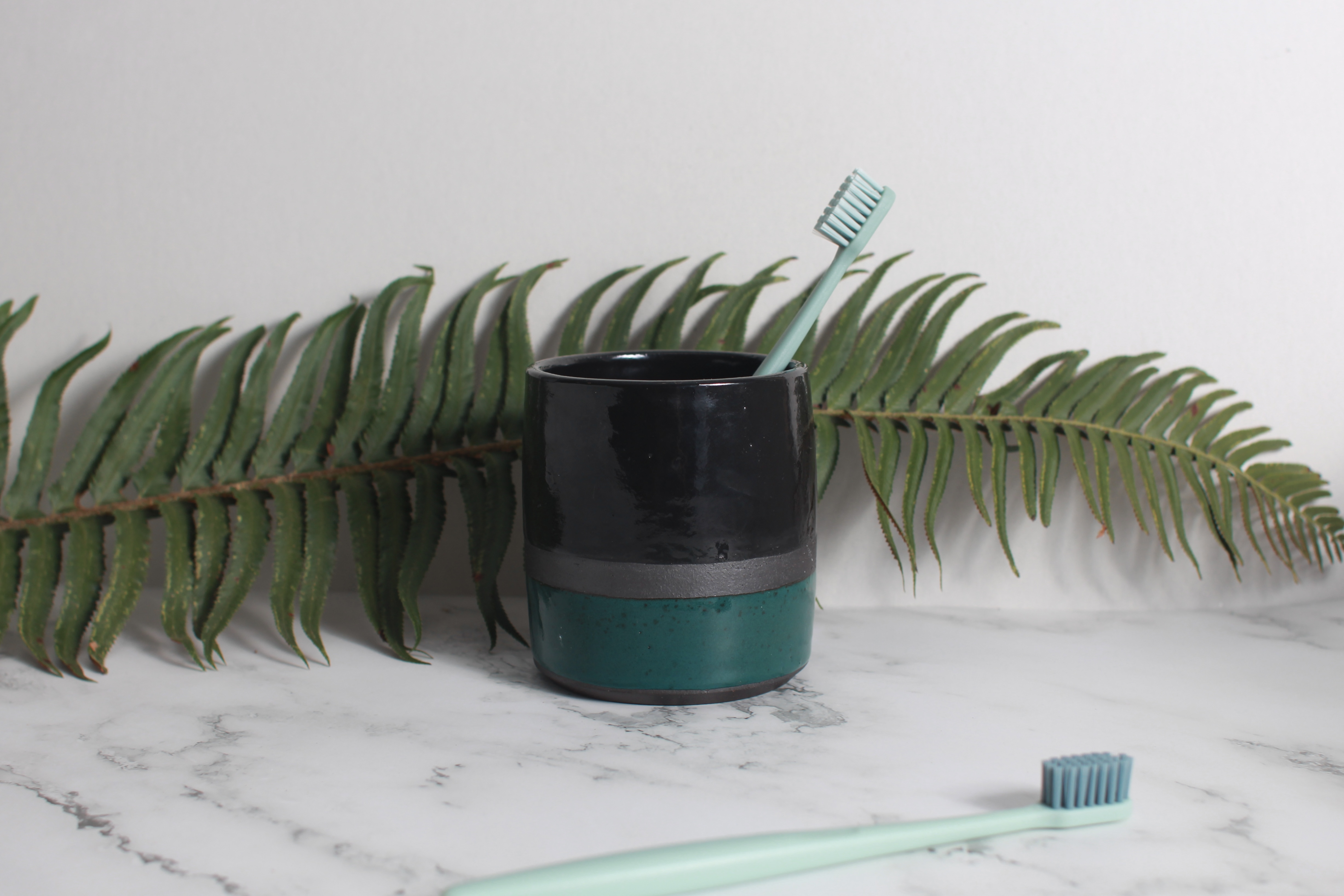 Black and green cup with toothbrushes